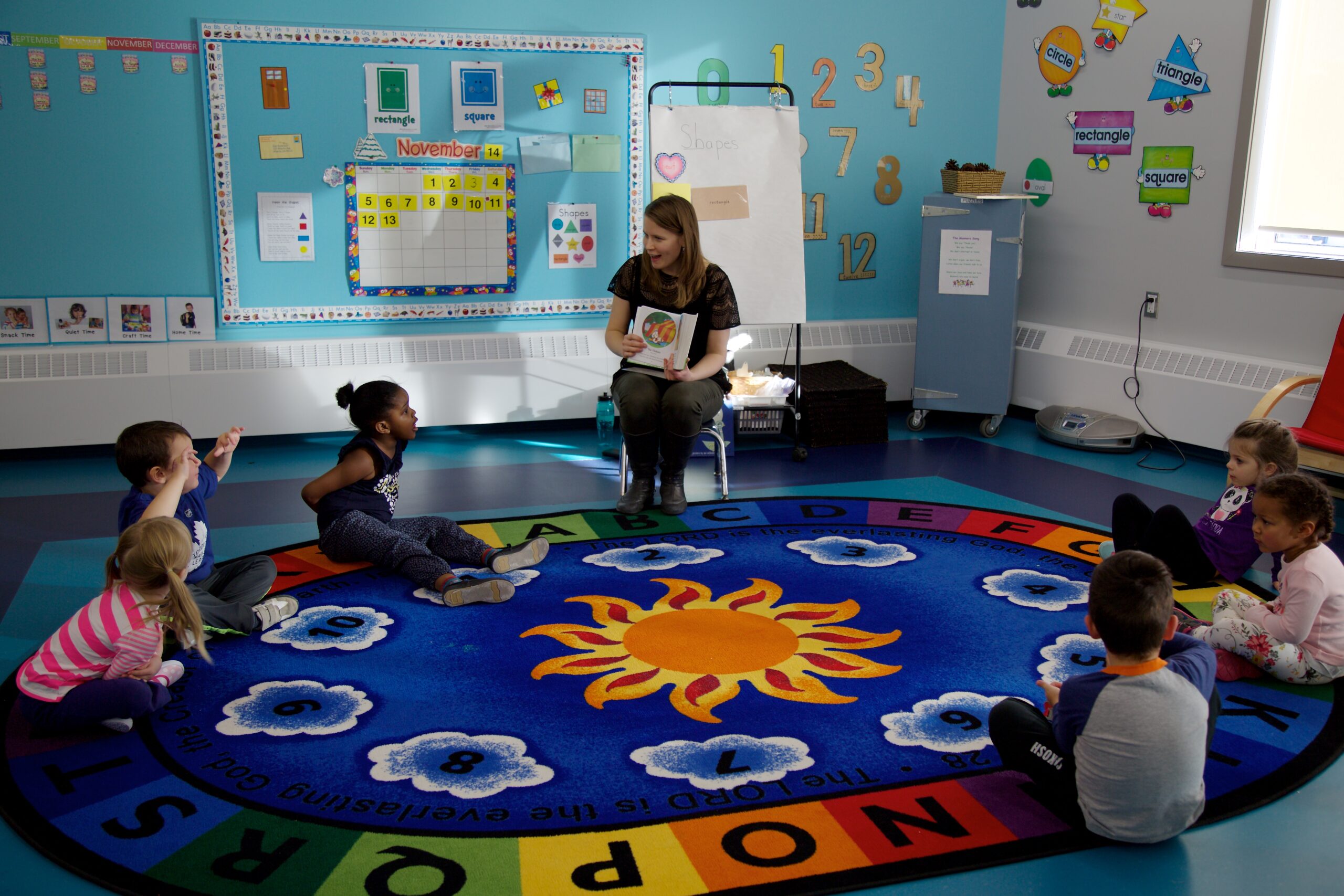 girl's left hand wrap around toddler while reading book during golden hour